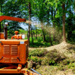 Landscapers using wood Chipper in Action captures a wood chipper or mulcher shooting chips over a fence.